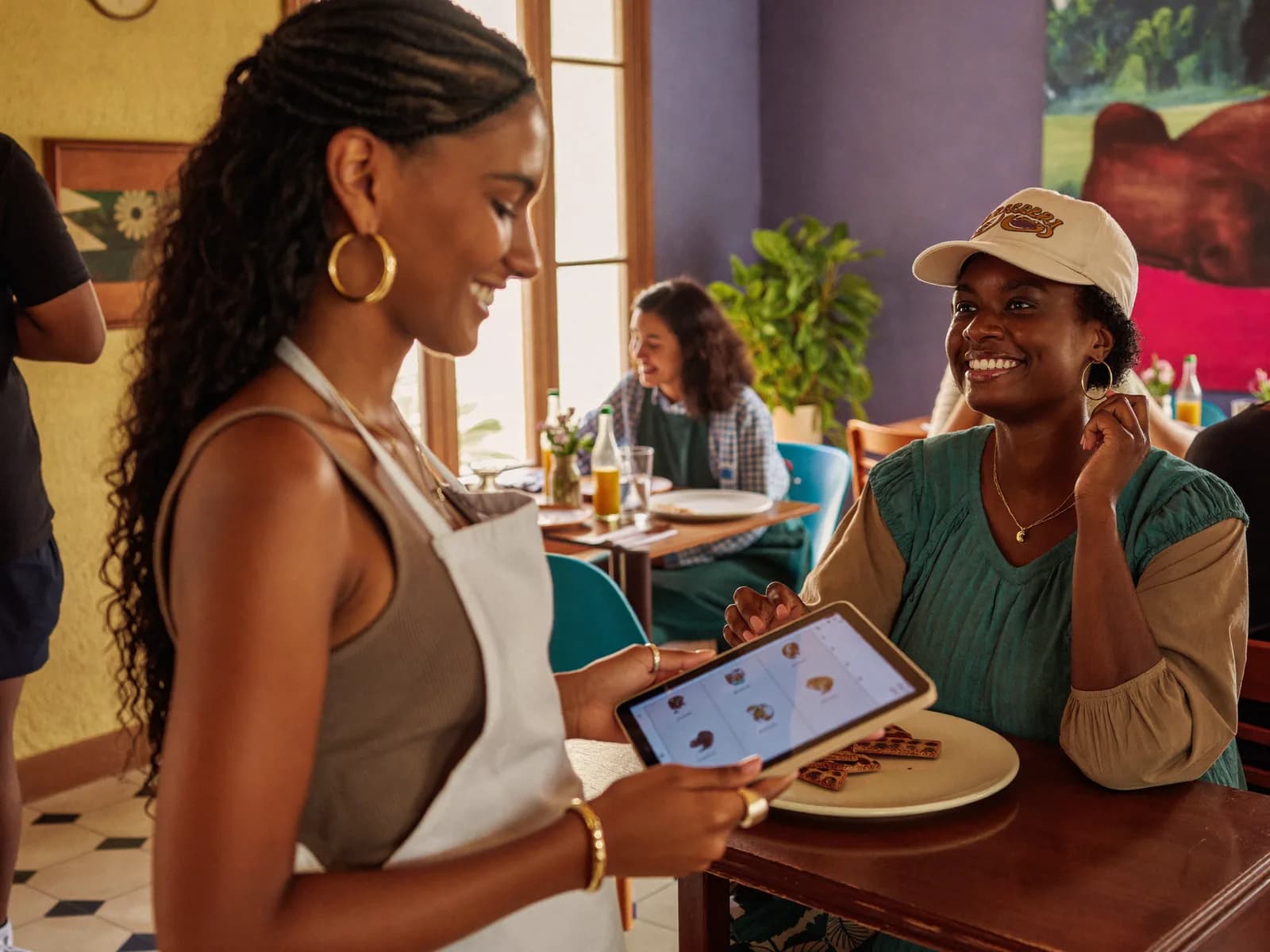 Serveuse prenant une commande sur tablette dans un restaurant haïtien